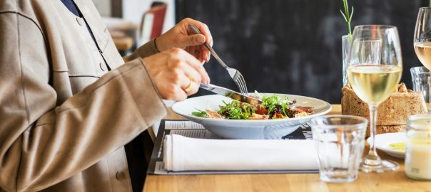 A person eating a salad at a restaurant table
